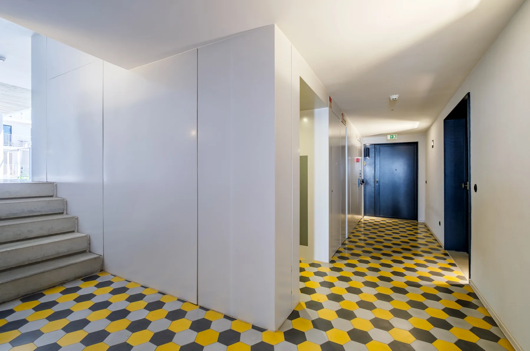 An interior hallway with patterned flooring and a staircase.