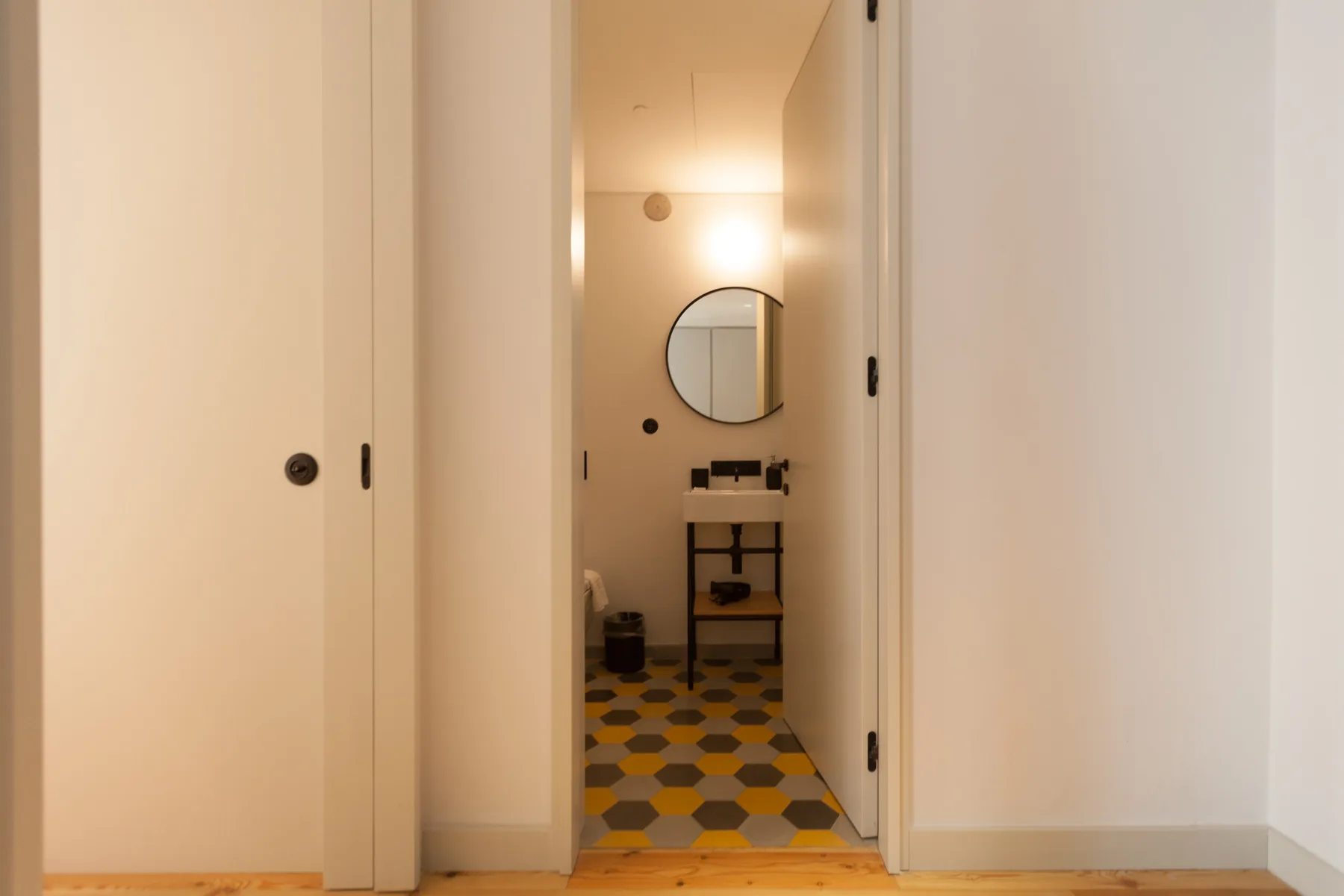 A bathroom is visible through the open doorway, with a round mirror above the sink.
