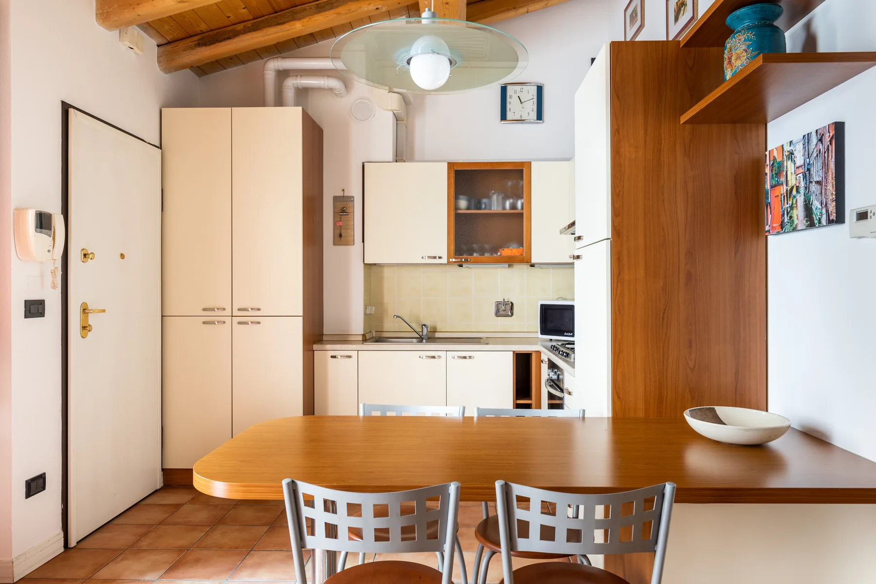 Un comedor con una mesa de madera y una cocina compacta al fondo.