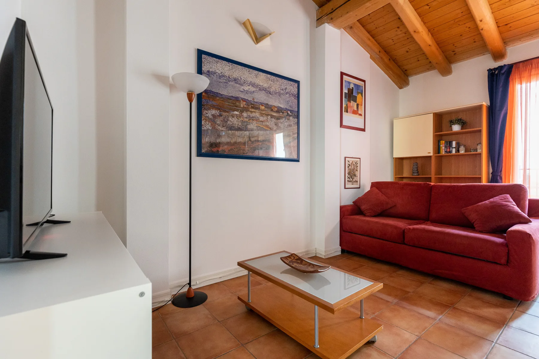 Una sala de estar con asientos rojos, una mesa de centro y un techo con vigas de madera.