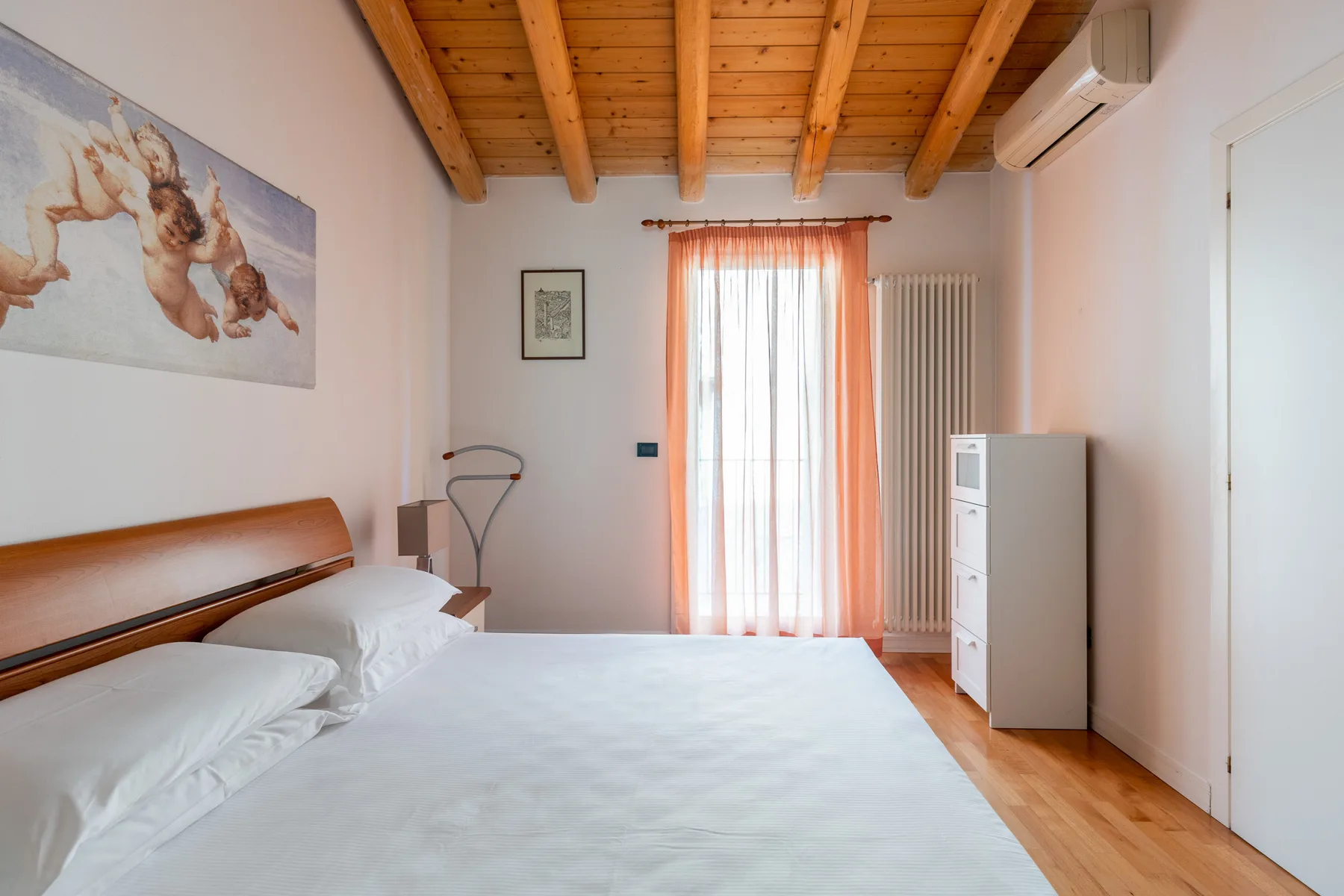 Un dormitorio con una cama, una ventana con cortinas y un techo de madera.