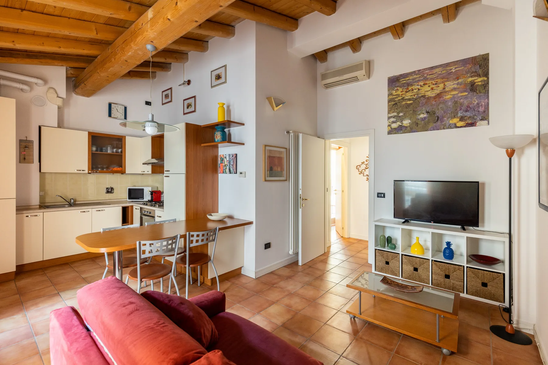 Sala de estar y cocina de espacio abierto con mesa de comedor y televisor.