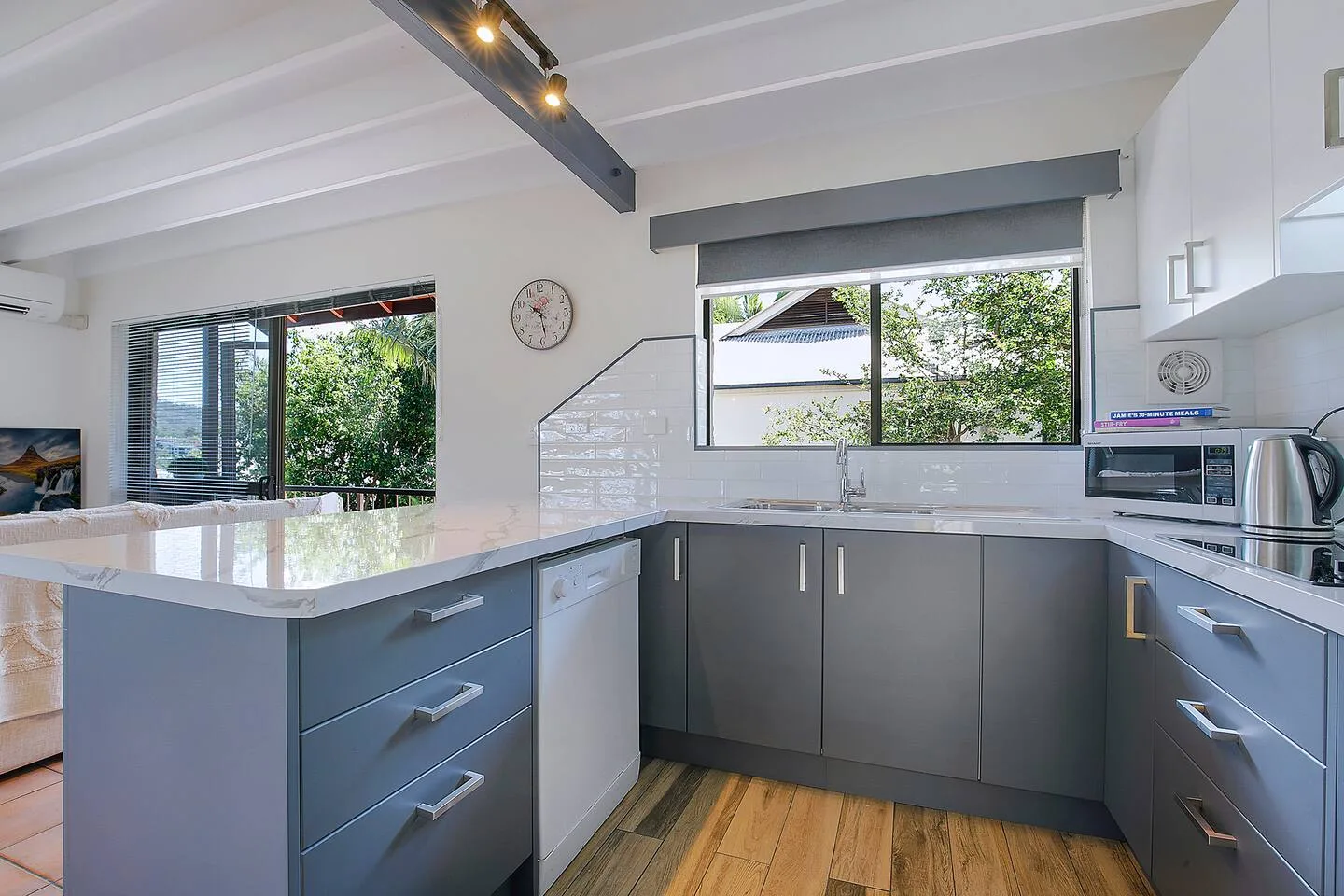 Una cocina moderna con gabinetes grises y una amplia encimera bajo las ventanas.