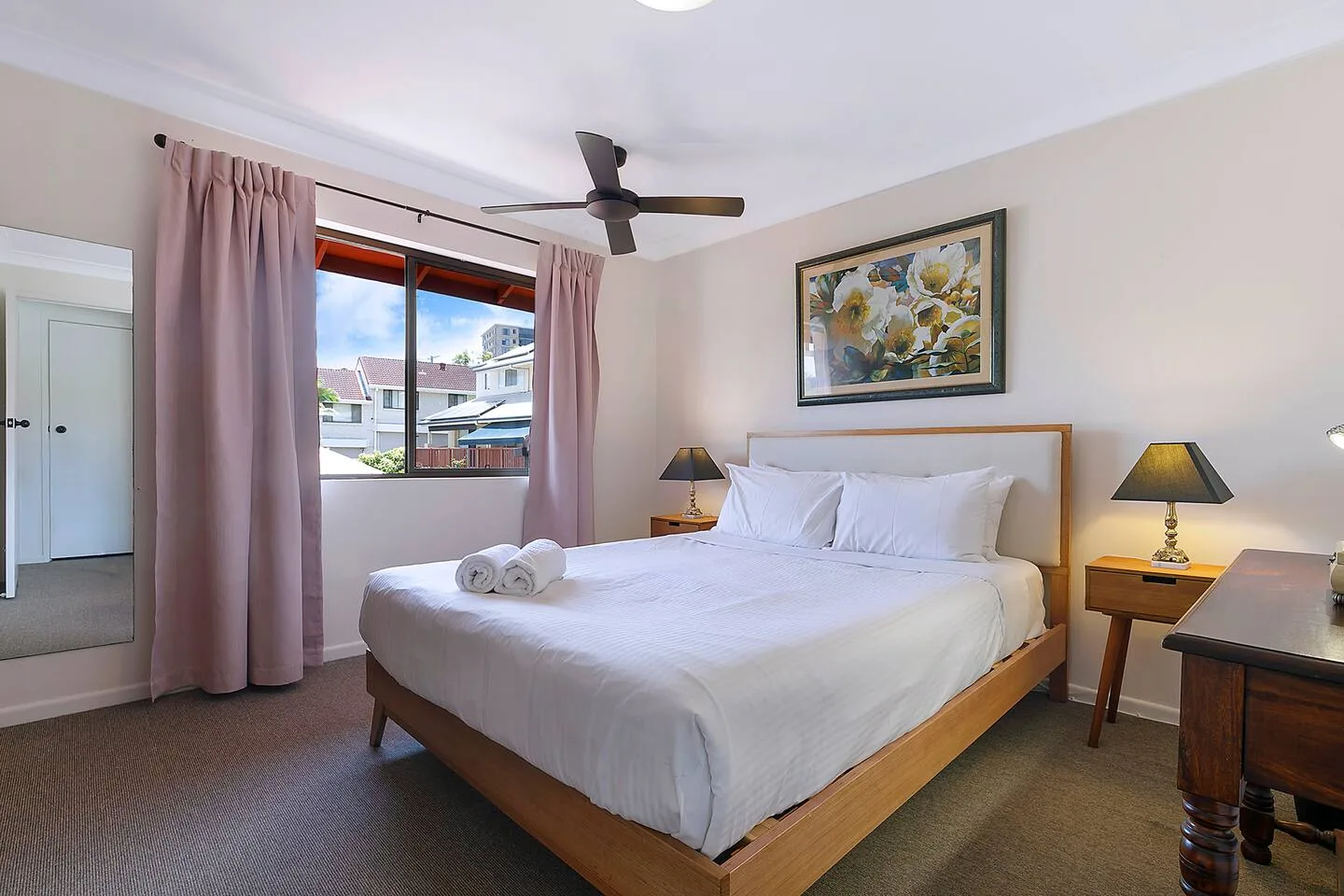 A bedroom with a bed, ceiling fan, and curtained window.