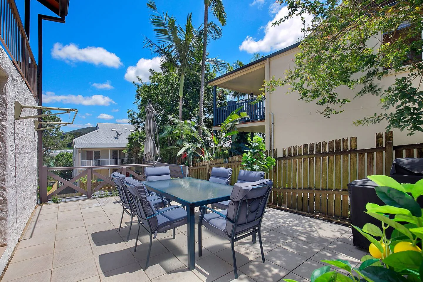 An outdoor dining patio with a table and seating beside a wooden fence.
