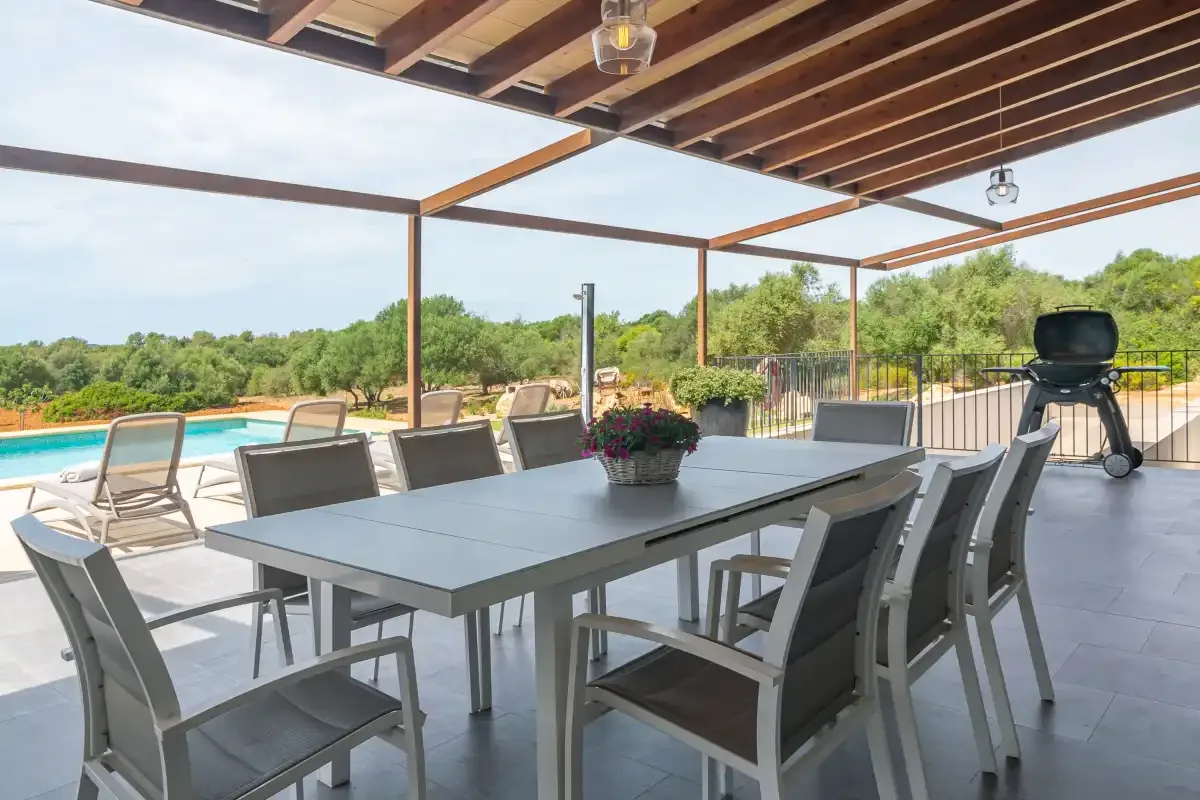 A covered outdoor dining area with a table and seating beside a pool.