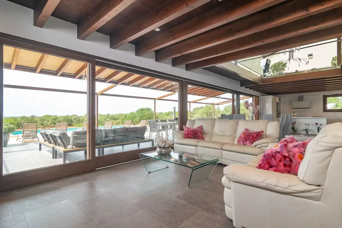 A living room with cream seating and wide glass doors opening onto a terrace.