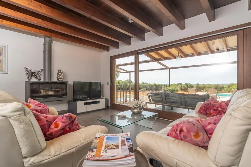 Living room with seating, a television, and wide glass doors opening to a covered patio.
