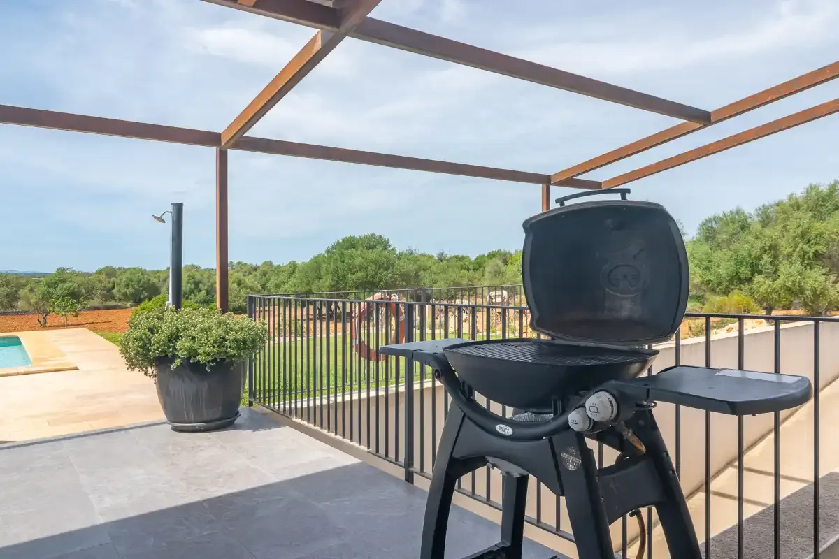 A rooftop terrace with an open barbecue beside a metal railing.