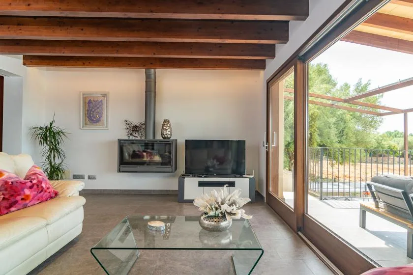 A living room with a glass coffee table beside large windows opening onto a patio.