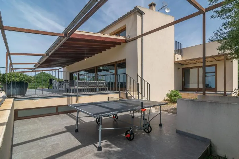 An outdoor terrace with a table tennis table beside a modern building.