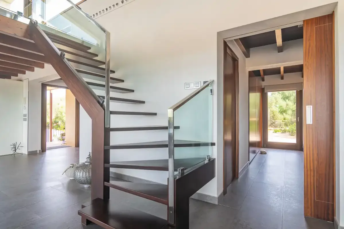 A bright interior hallway features a staircase and an open doorway to the outside.