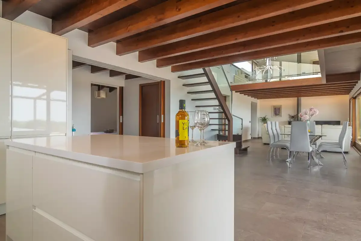 An open-plan kitchen and dining area with a large island and overhead timber beams.