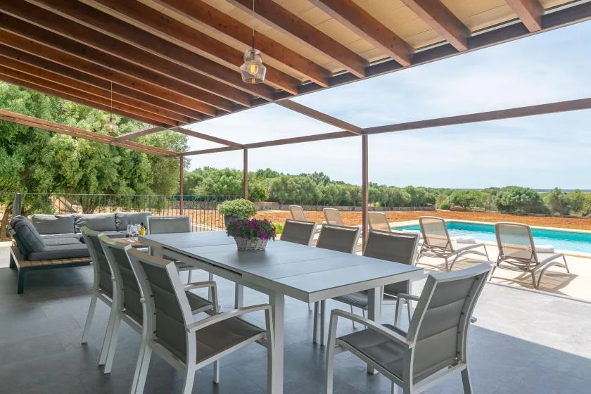 A covered outdoor dining area overlooks a patio with a swimming pool.