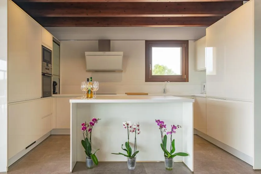 A bright modern kitchen with a central island and flowers.