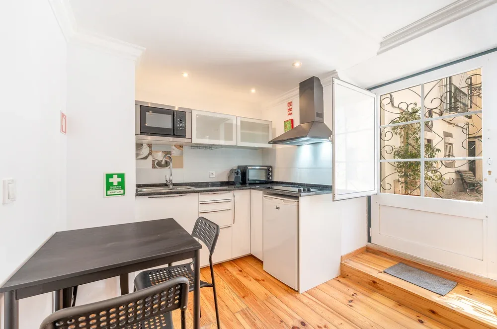 A bright kitchen with a dining table and a window overlooking a courtyard.