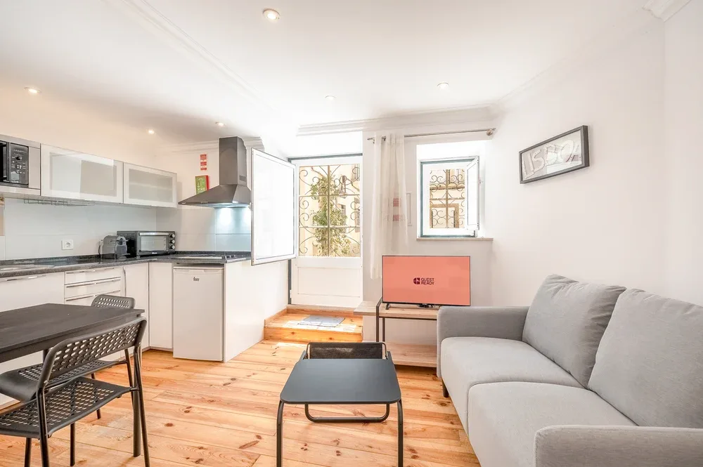 A bright kitchen and living area with a gray sofa and a small table.