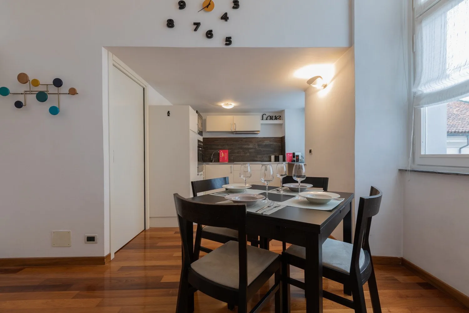 Un comedor con una mesa oscura y sillas junto a una cocina compacta.