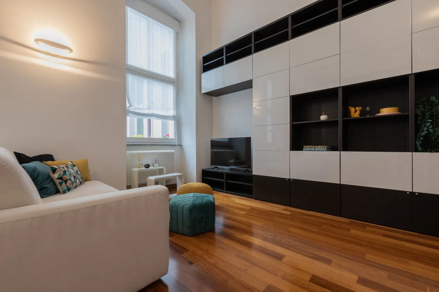 Una sala luminosa con una ventana grande, estanterías empotradas y asientos.