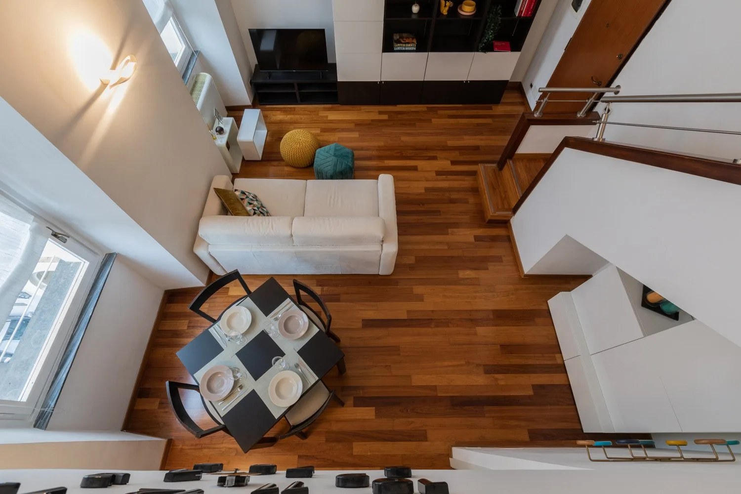 Una sala luminosa con suelo de madera, un sofá y una mesa de comedor.