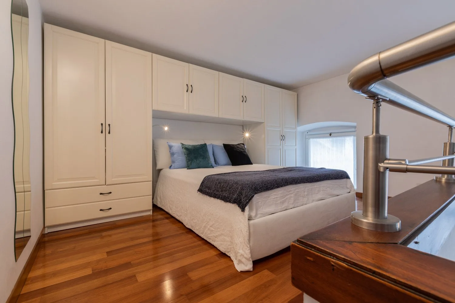 Un dormitorio con una cama, armarios empotrados y suelo de madera pulida.