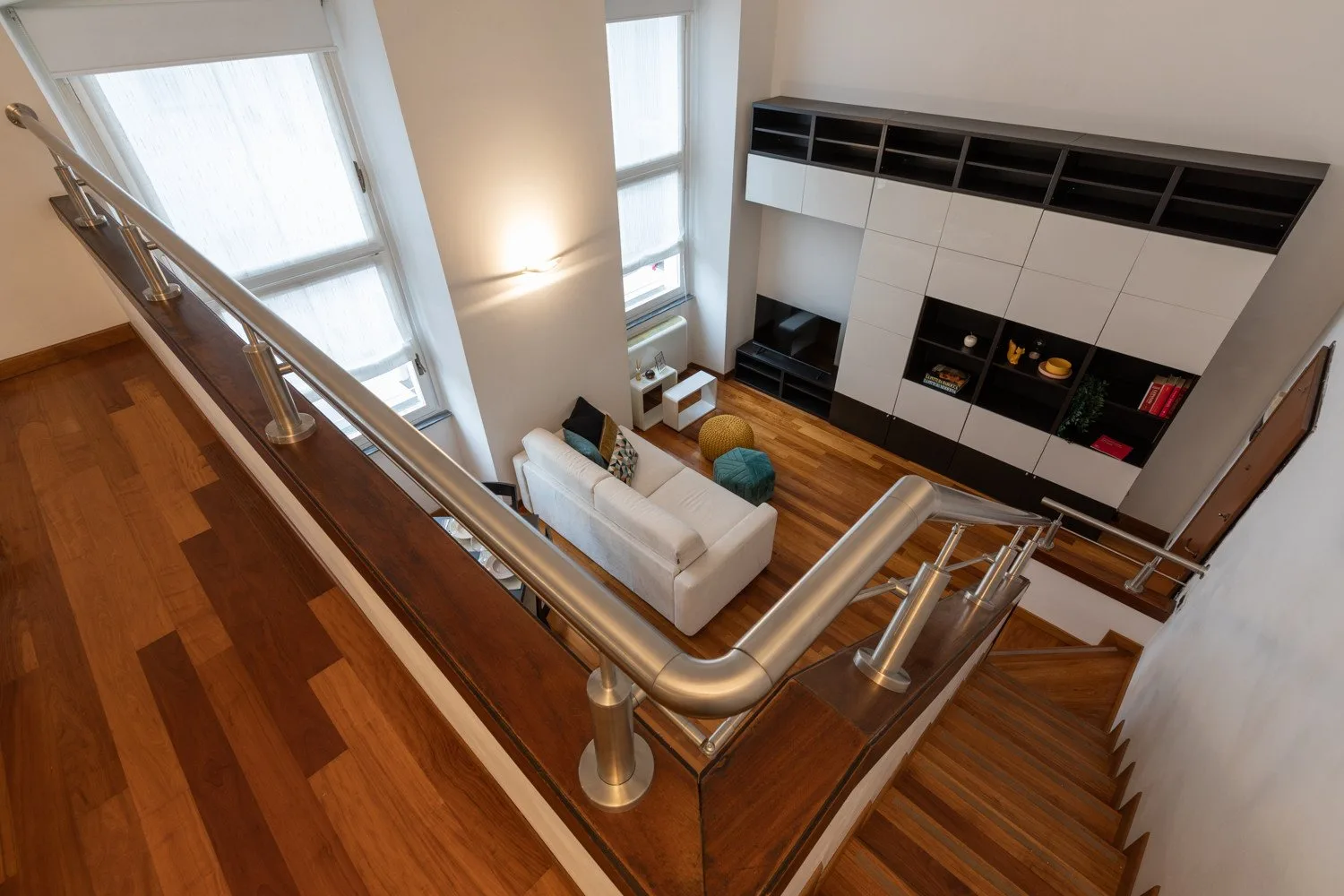Una sala de doble altura con una zona de estar blanca y un gran mueble empotrado.