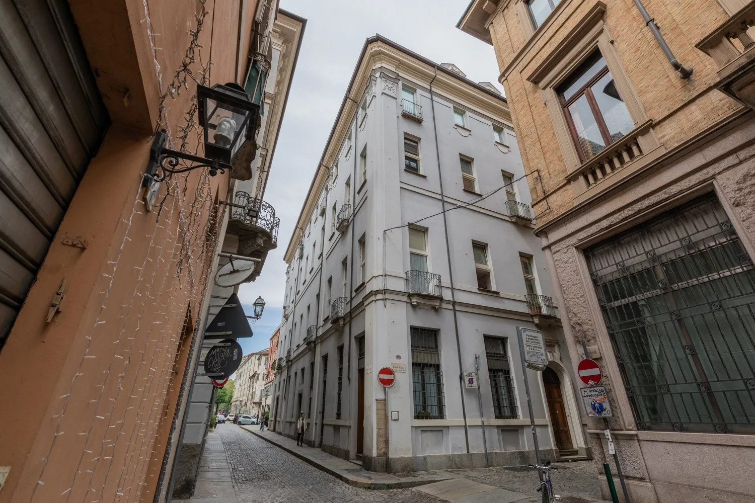 Una calle estrecha de adoquines pasa entre edificios de varias plantas muy próximos.