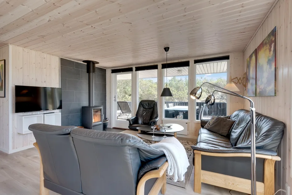 A bright living room with seating, a wood stove, and large windows.