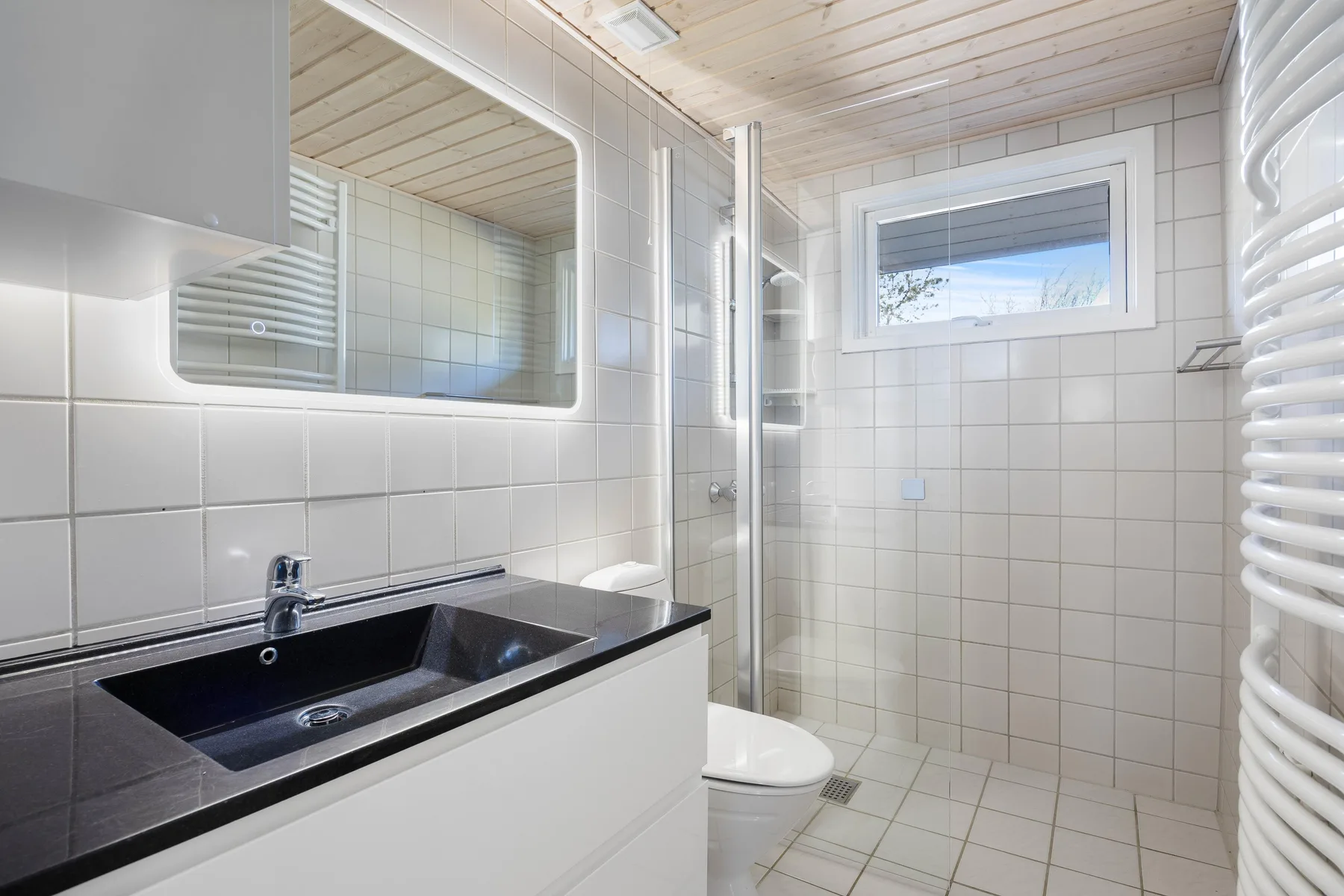A tiled bathroom with a sink, mirror, and shower.
