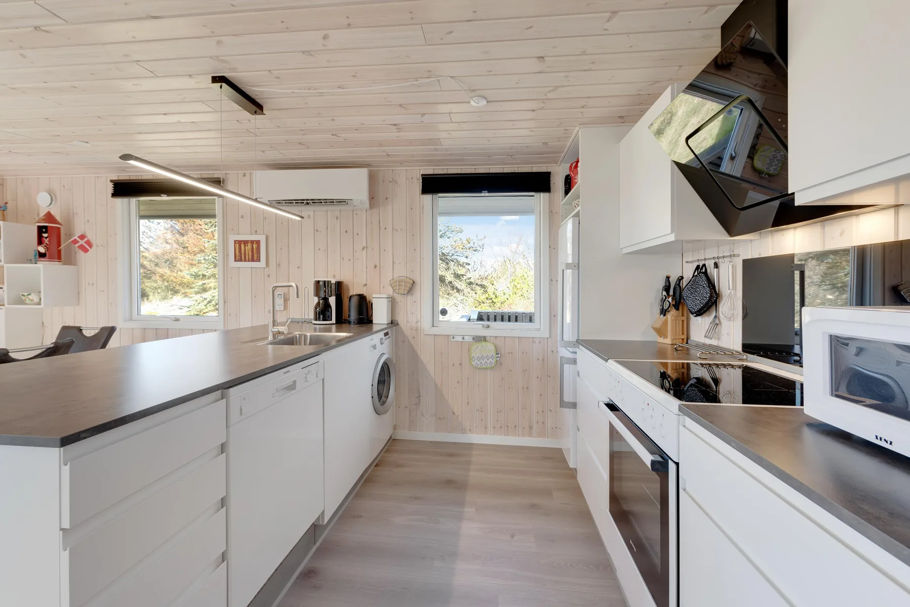 A bright kitchen with white cabinets, countertops, and windows.
