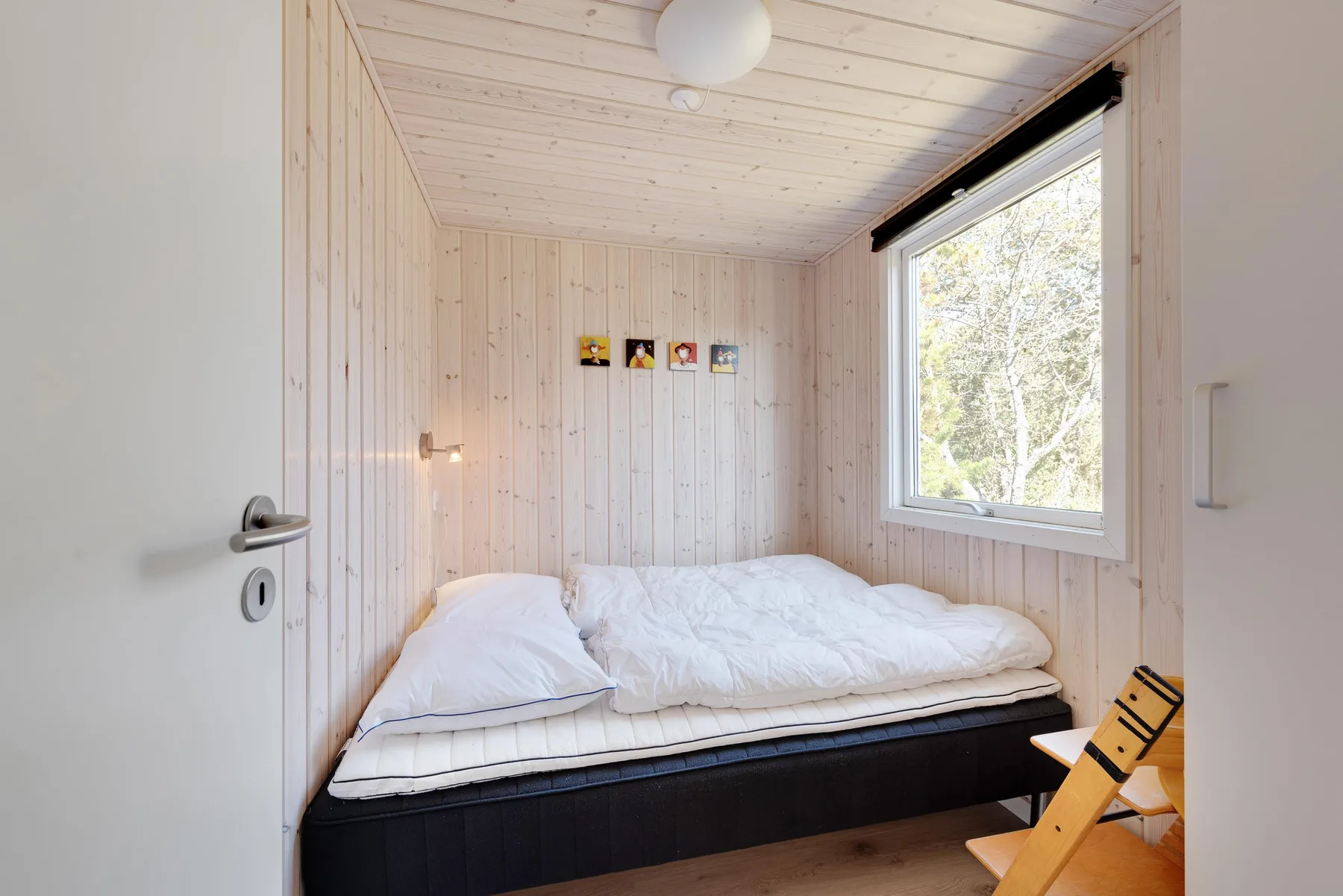 A compact bedroom with a bed beneath a large window.