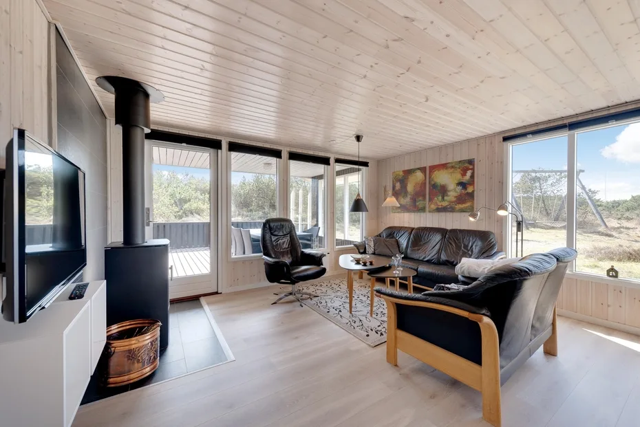 Living room with seating around a coffee table beside large windows.