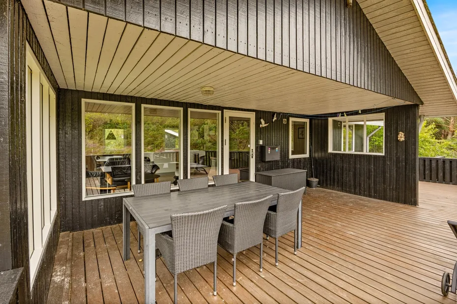 A covered outdoor dining area with a table and seating on a wooden deck.