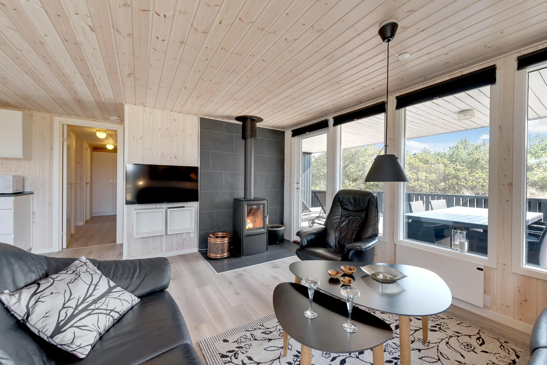 A living room with seating, a wood stove, and large windows.