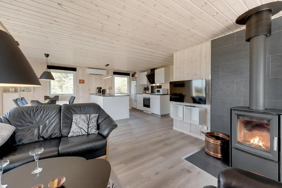 An open-plan living room and kitchen with seating and a lit fireplace.