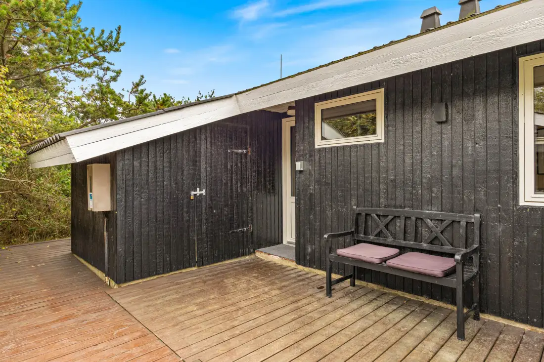 A dark wooden cabin exterior with a deck and outdoor seating.