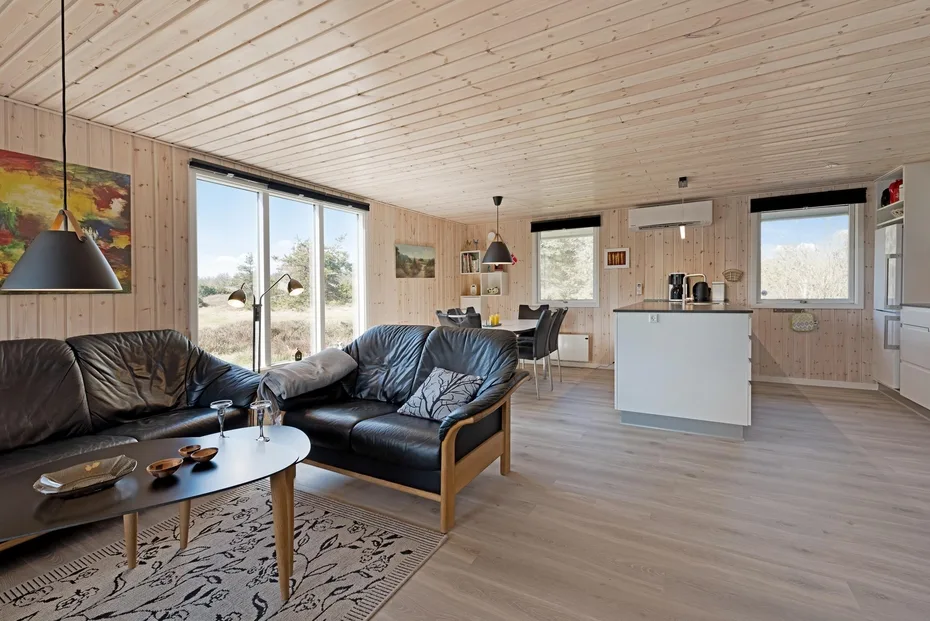 An open-plan living area with dark seating and a kitchen island.