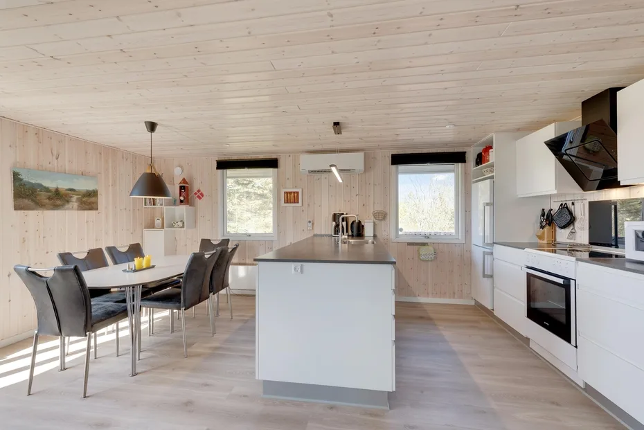 A bright open-plan kitchen and dining area with a central island and dining table.