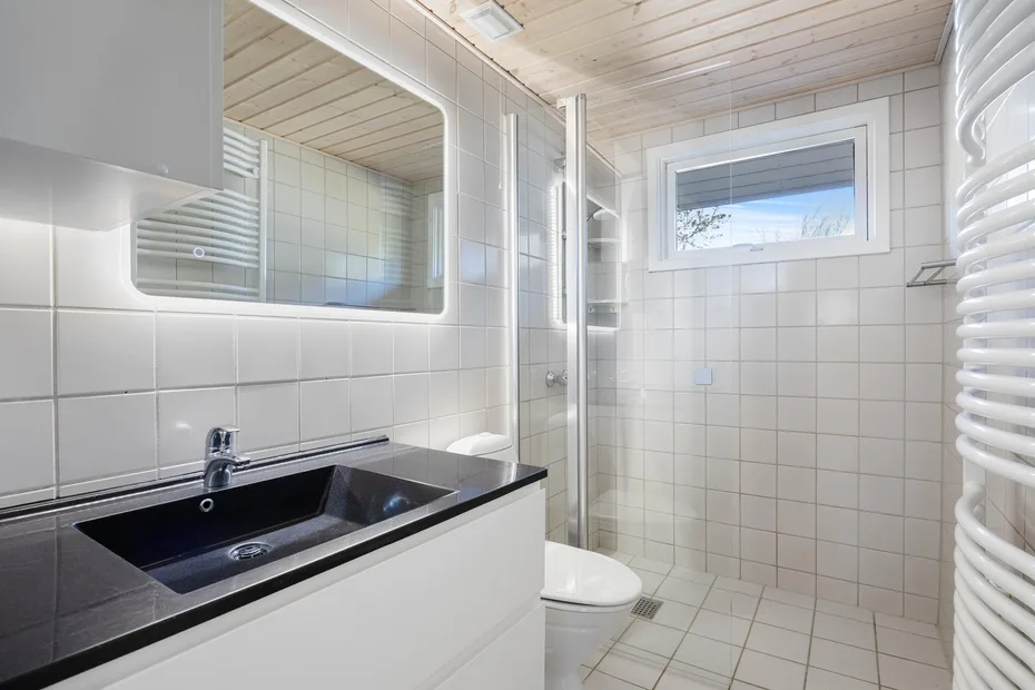 A tiled bathroom with a sink, toilet, and glass shower area.