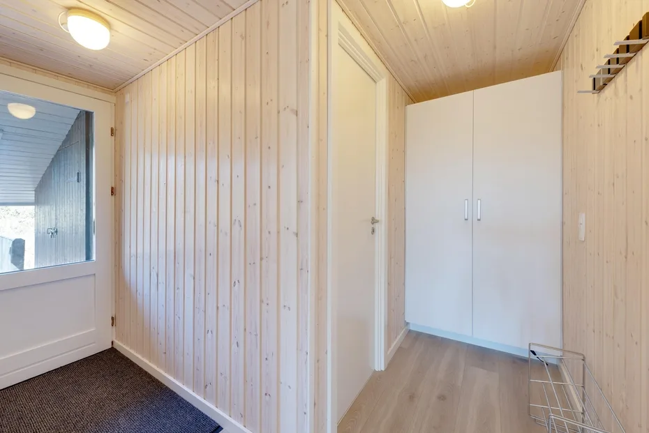 A wood-paneled entry area with a white wardrobe and a glazed door.