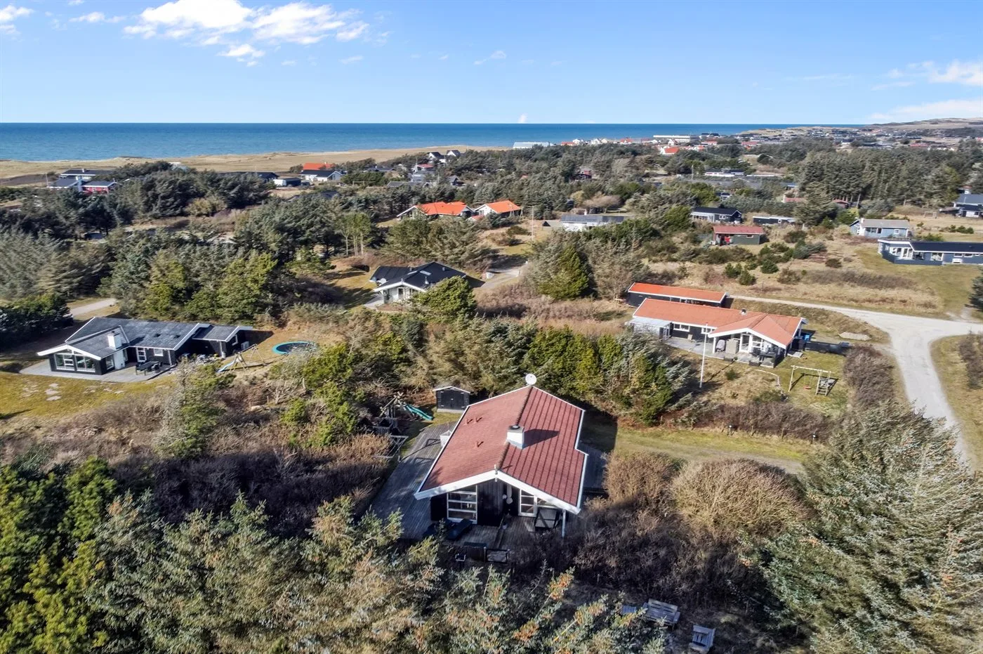 Vista aérea de casas dispersas entre vegetación junto a la costa.