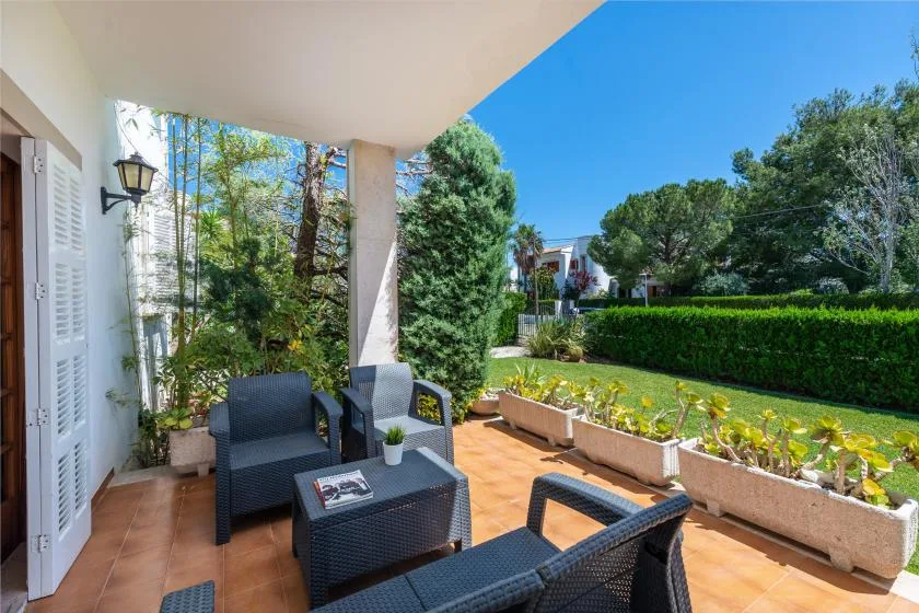 A covered outdoor patio has dark seating beside raised garden planters.
