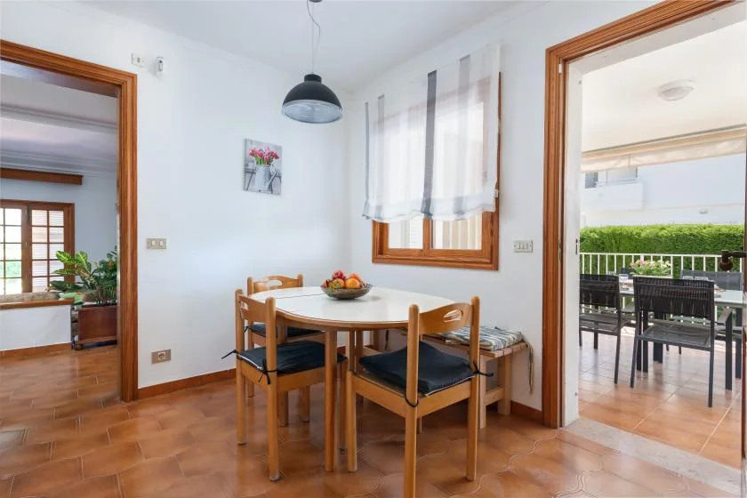 A dining area with a wooden table and chairs beside windows and an open doorway.