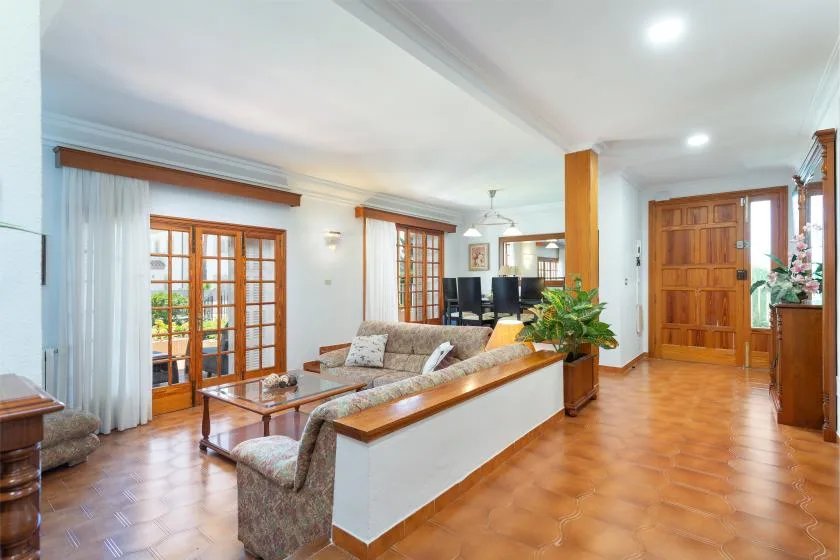 A living room with seating, a television, and wooden-framed glass doors.
