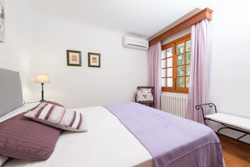 A bedroom with a bed beside a window framed by pink curtains.