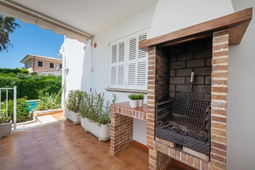 A covered patio with a brick fireplace and potted plants.