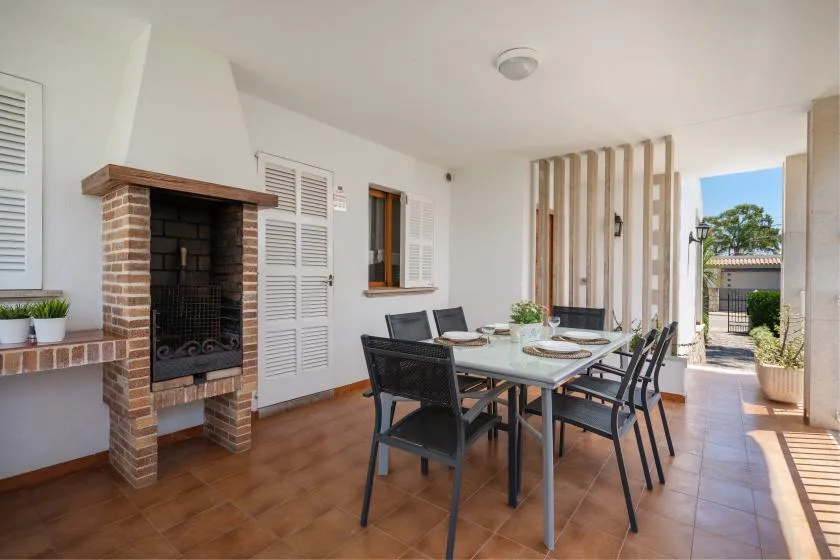 A covered patio dining area with a table and built-in brick fireplace.