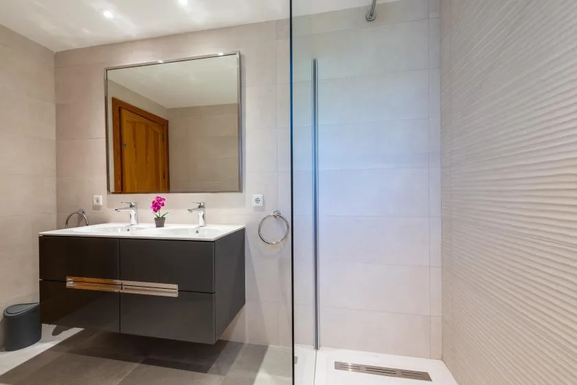 A modern bathroom with a floating vanity and glass shower.