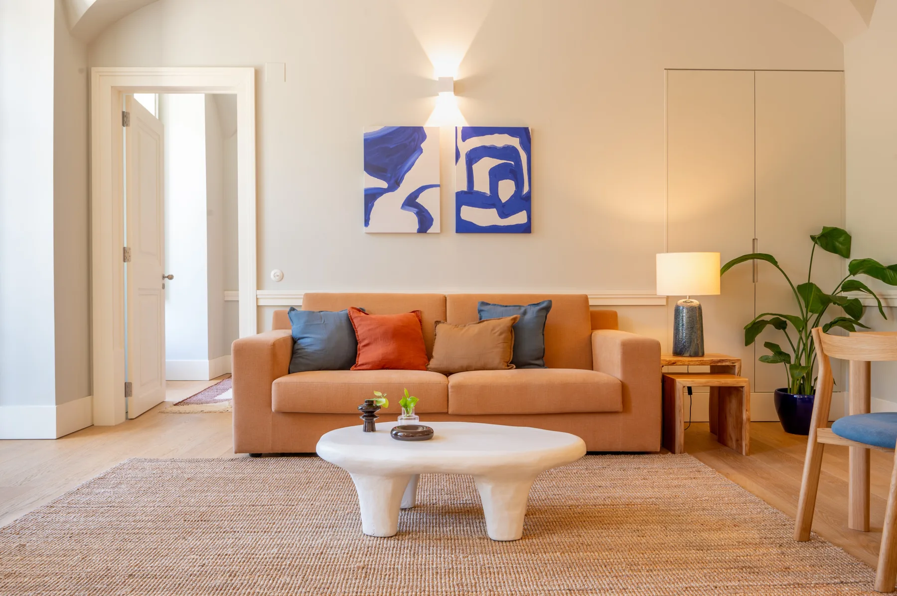 Sala de estar con sofá, mesa de centro y arte abstracto en la pared.