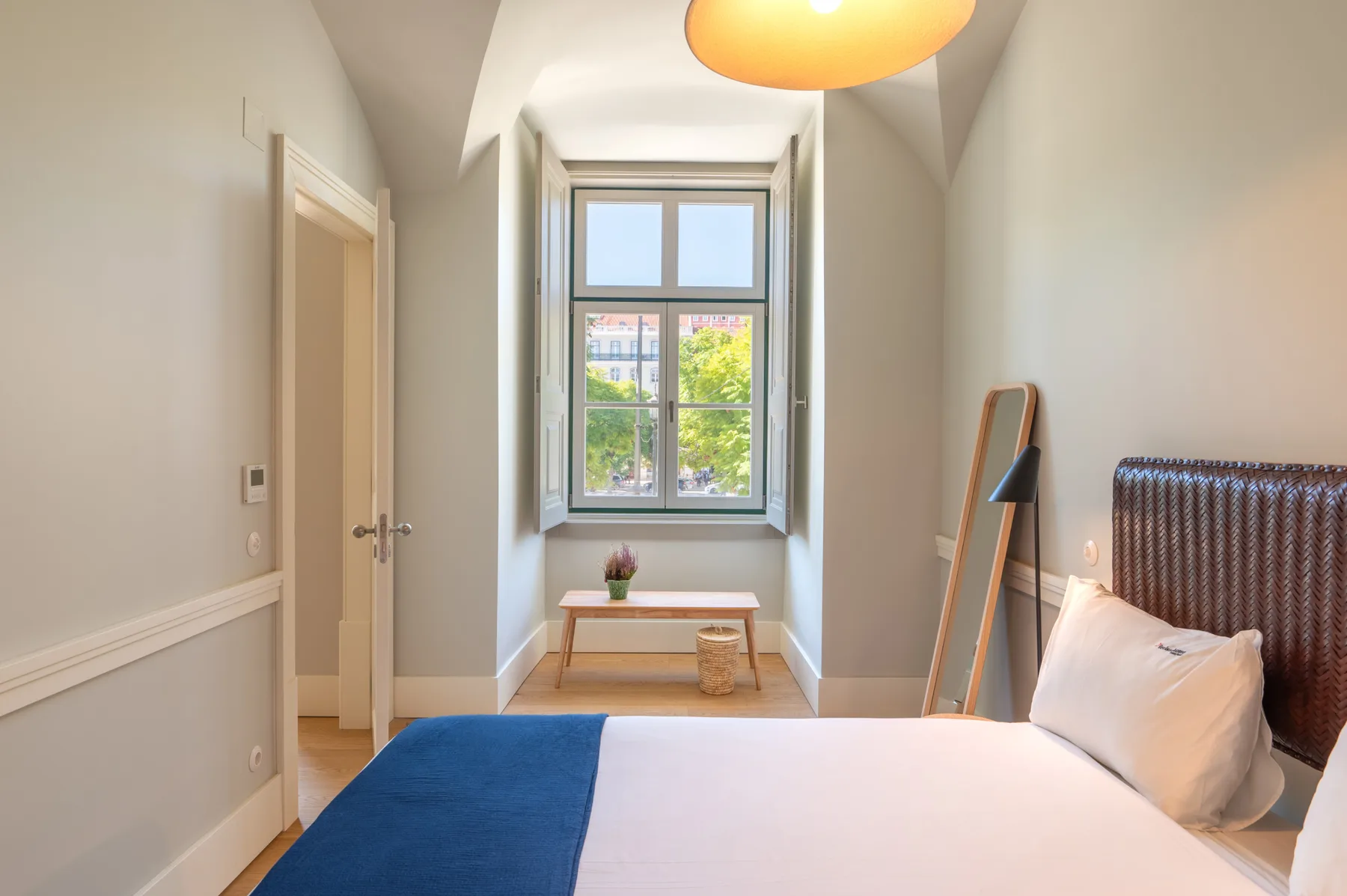 A bright bedroom with a bed beneath a large window.